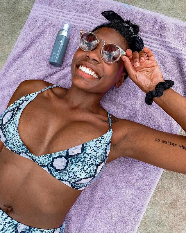 Creator suntans with COSMEDIX product on her towel