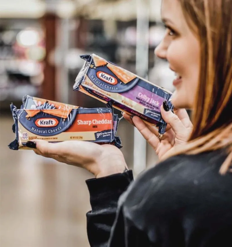 Woman holds Kraft sharp cheddar and Kraft colby jack