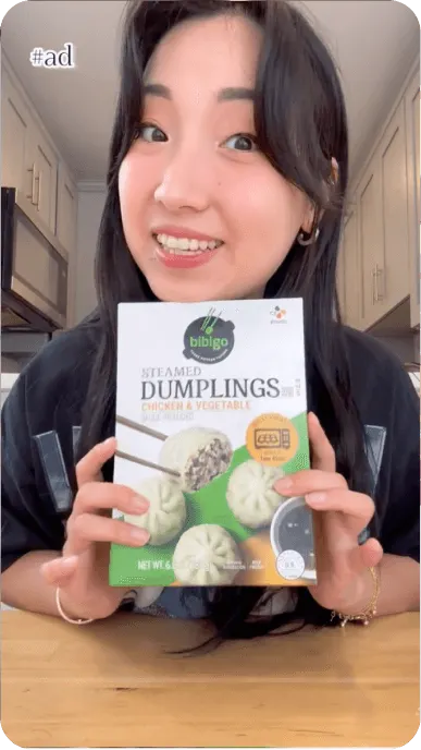 Creator holds a box of bibigo steamed chicken and vegetable dumplings