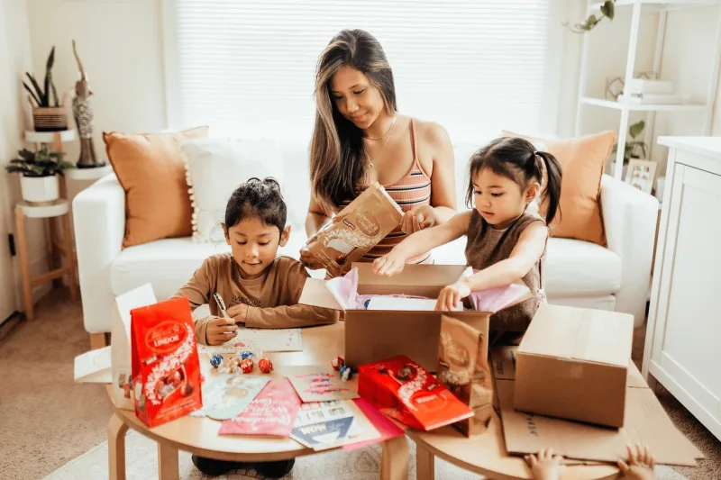 Woman wraps gifts with two children