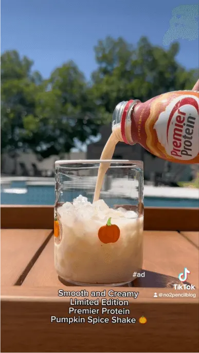 Image of pumpkin spice protein shake poured over ice in a glass with pumpkin detail