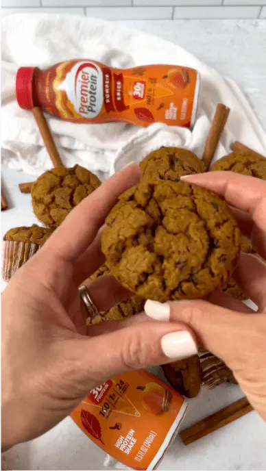 Creator holds muffins made with pumpkin spice protein shake with premier protein bottle in background